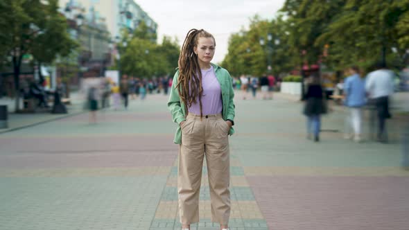 Zoomin Time Lapse of Unique Girl with Dreadlocks Hairdo Standing Outdoors in City Street Among Crowd