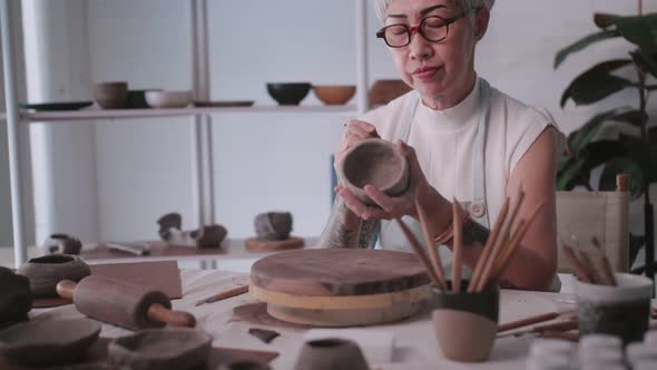 Asian elderly woman enjoying pottery work at home.