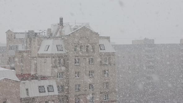 Heavy snowfall on city streets. Traffic of cars on snowy streets. View from window.