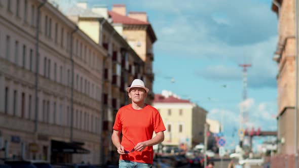 Young man walking along city street, camera tracking