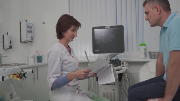 Doctor Cardiologist in the Office of Ultrasound Diagnostics with the Patient Examines Medical Tests