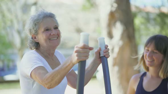 Happy Senior Woman Exercising on Elliptical Trainer in Park