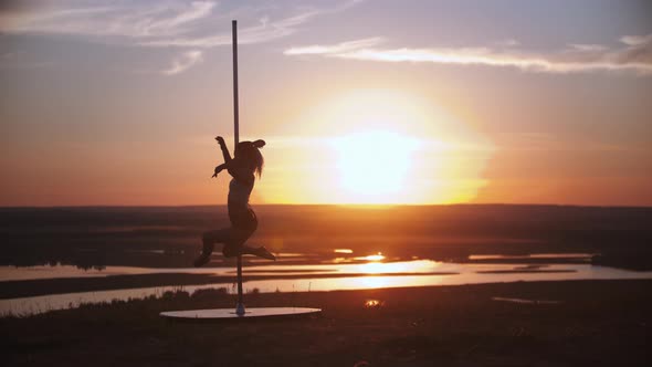 Young Woman Spinning on the Dancing Pole on Sunset