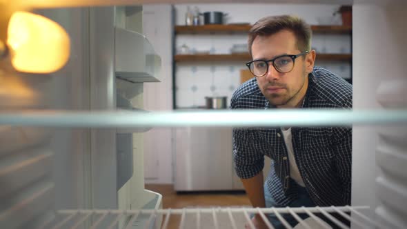 Hungry Young Man Looking for Food in Empty Fridge