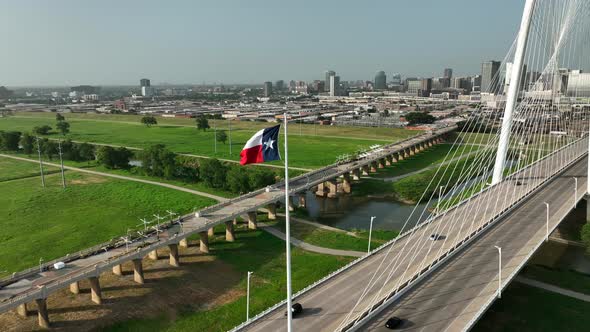 Aerial of Texas flag flying proudly in Dallas, TX at Margaret Hunt Hill Bridge over Trinity River. B