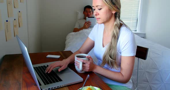 Woman using laptop while man using digital tablet