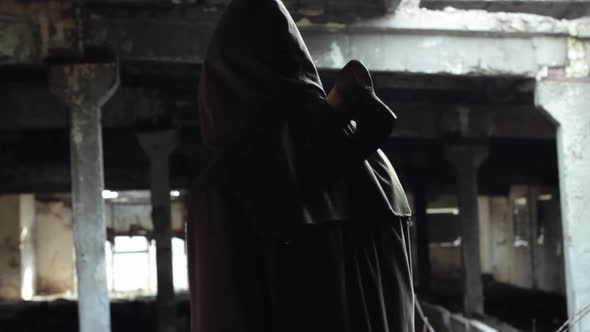 a Man in a Dark Cloak with a Bloody Ax Walks in a Dark Abandoned Room