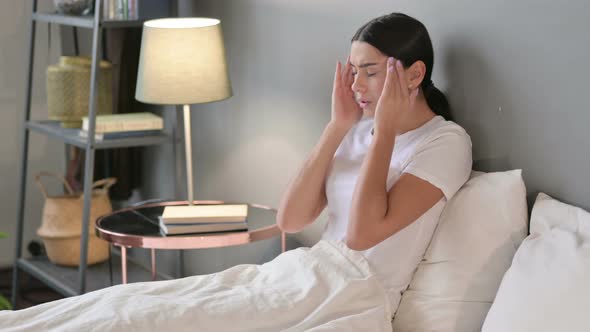 Young Latin Woman with Headache Sitting in Bed 