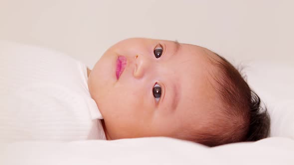 happy newborn baby lying on a white bed and blanket comfortable and safety