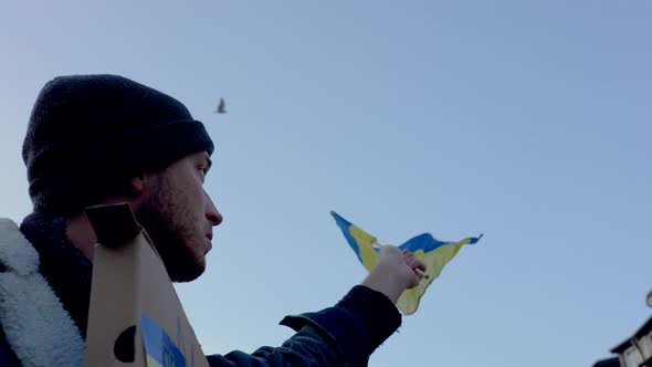 Activist waving Ukrainian flag at protest in Prague, bird flying over.