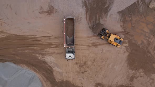 Excavator Loading Sand Into Large Truck Aerial View