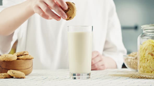 Eating Cookie with Milk in Glass Cup Closeup