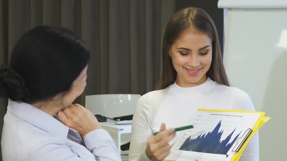 Young Businesswoman Showing Diagrams To Her Senior Colleague