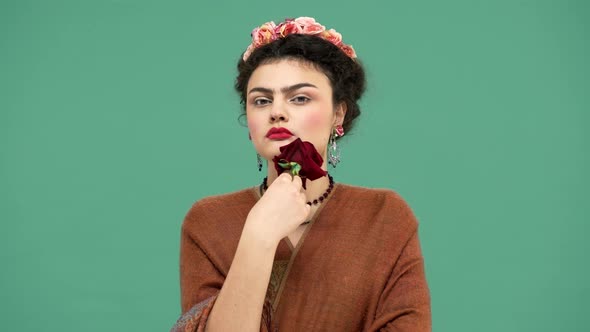 Fashion Portrait of Brunette Mexican Woman As Famous Artist Frida Kahlo Holding Red Big Rose and