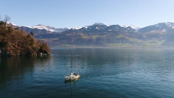 Aerial video of a sail boat cruising Lake Lucern, Switzerland at sunset. 