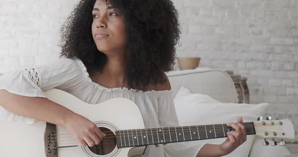 A Beautiful Black Woman Playing the Guitar and Enjoying a Quiet Time at Home