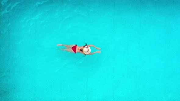 View From the Top As a Woman in Red Swimsuit Swims in the Pool