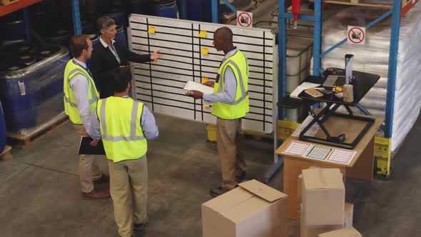 Staff meeting at an information board in a warehouse 4k