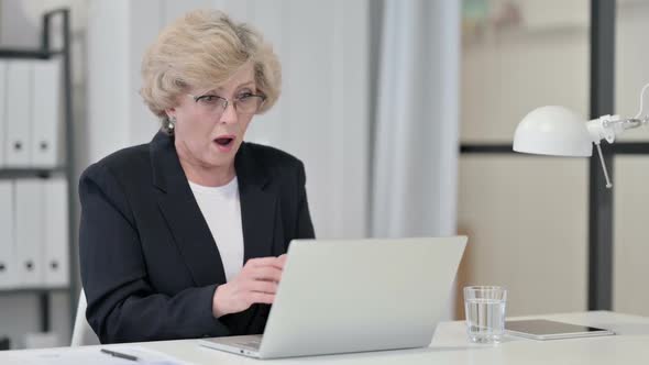 Old Businesswoman Feeling Shocked While Working on Laptop