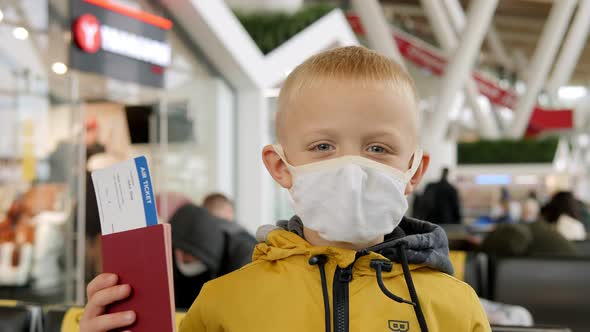 A Little Boy in a Medical Mask at the Airport with a Passport and Ticket