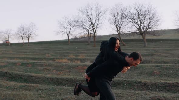 Young People in Love Fool Around on the Green Meadow at Sunset