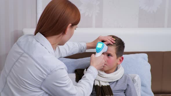 Woman Measures Son High Body Temperature with Noncontact Thermometer in Celsius and Worries About