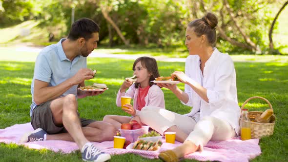 Family Eating Sandwiches on Picnic at Summer Park