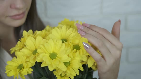 A bouquet of yellow chrysanthemums in the hands of a girl.