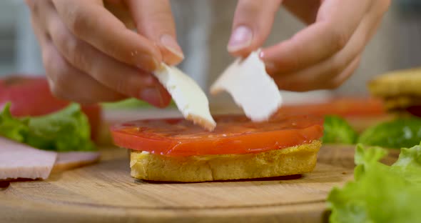 Female Chef in the Kitchen of the House Collects a Sandwich