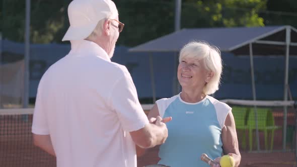 Smiling Mature Couple Shaking Hands After Playing Tennis on the Tennis Court