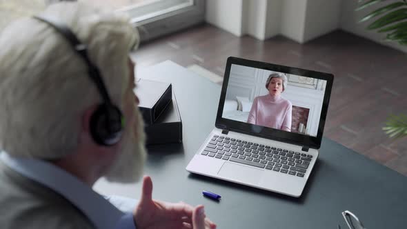 Over the Shoulder View of an Elderly Man Video Call To Wife Using a Laptop. The Concept of Family