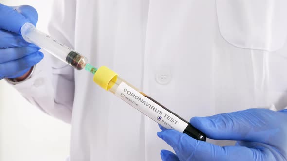 The syringe medical analyst analyzes blood from a Covid-19 positive test tube