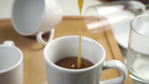 Pouring fig jam into a white tea cup in slow motion on the kitchen table