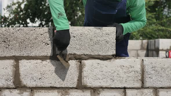 Mason Puts the Brick of Outer Wall of Building. Bricklayer Installation of Concrete Blocks