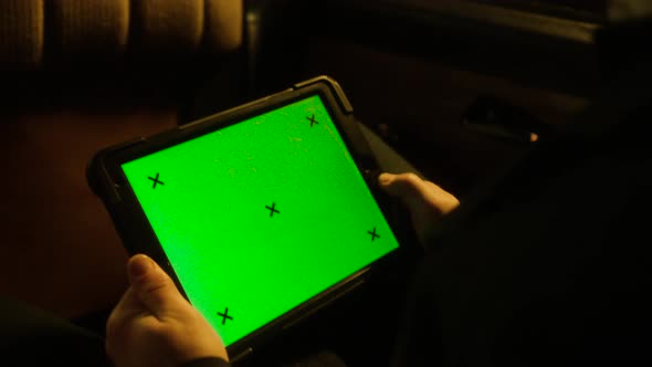 Man holding tablet with green screen in car