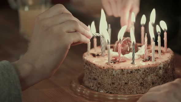 Two People Lighting the Candels on a Birthday Cake