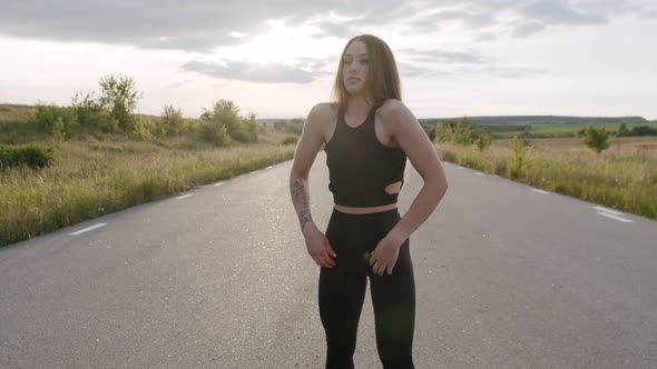 Pretty Sports Girl Doing Arms Warmingup on Road at Summer Nature in Morning