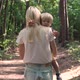 The camera follows a woman walking through the forest holding her son in her arms. - VideoHive Item for Sale