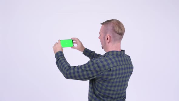 Rear View of Blonde Hipster Man Taking Picture with Phone