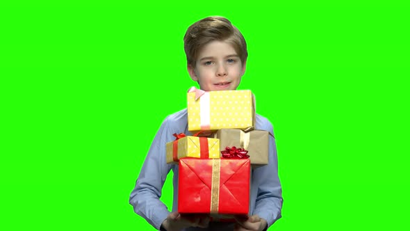 Portrait of Little Boy Holding Lots of Gift Boxes in His Two Arms