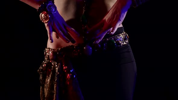 the Belly and Body of a Woman Dancing Oriental Dance in the Studio Making Beautiful Movements with