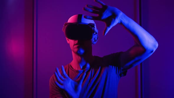 Man in a Virtual Reality Helmet Illuminated in Red and Blue Plays a Game