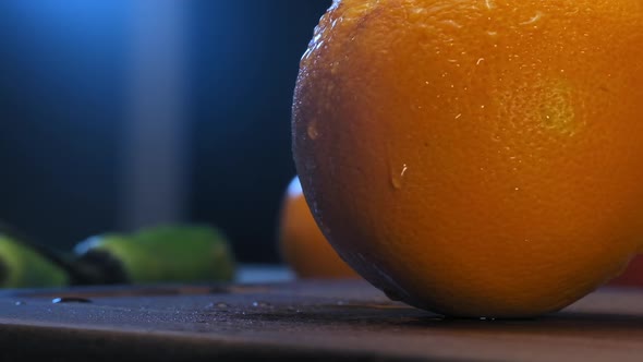 Small Water Drops Flow Over Orange on Brown Wooden Board