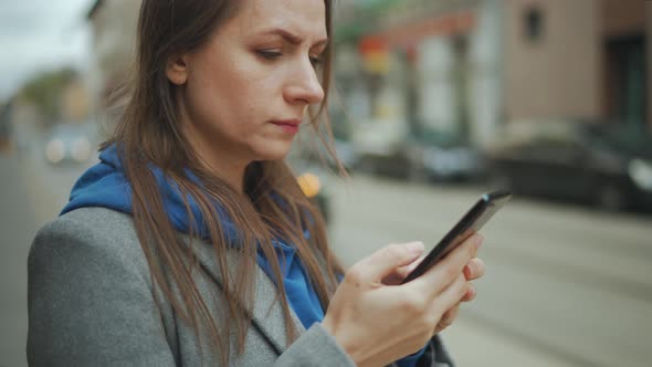 Woman Stands at a Public Transport Stop and Checks the Timetable