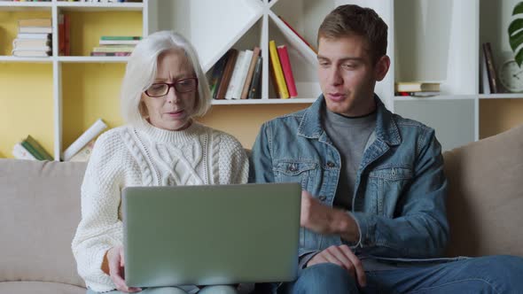 Man Teaching His Mother Using Laptop at Home, Technology Concept.