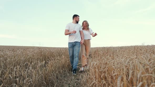 Young Man and Woman Walking Through the Wheat Field