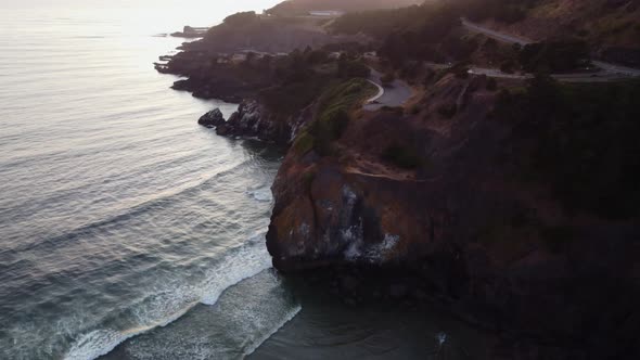 Drone shot of waves crashing onto the jagged cliffs at Yaquina Point in Newport, Oregon during sunse