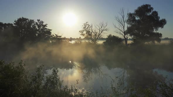 Pannnig Shot of Sunrise Reflected in a Misty Rive