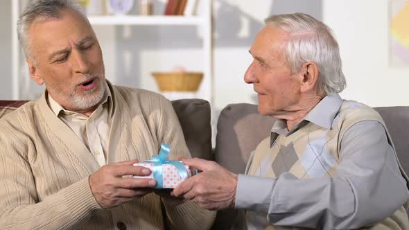 Male Pensioner Presenting Gift Box to Friend, Birthday Surprise, Congratulation