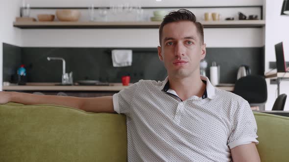 Portrait of Happy Man Is Resting While Sitting on Couch at Home. A Young Male Enjoys the Lifestyle